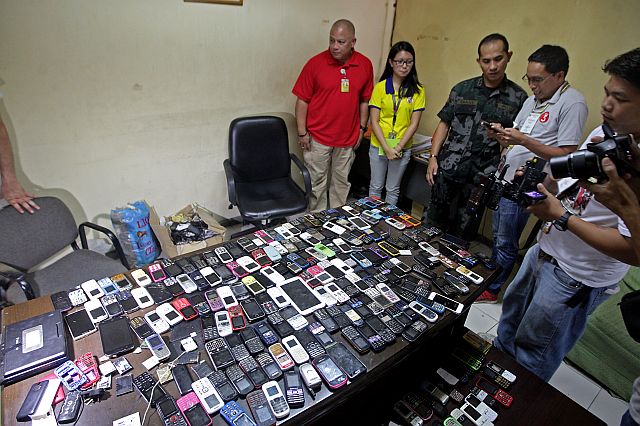 Provincial jail assistant warden Bobby Legaspi (red) presents to media the cellphones that were turned over by inmates to jail authorities (CDN PHOTO/TONEE DESPOJO).