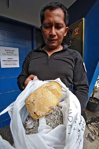 A SWAT policeman holds the opened box of what was earlier thought to be a bomb. The box was found to only contain sand, gravel and nails.(CDN PHOTO/JUNJIE MENDOZA)