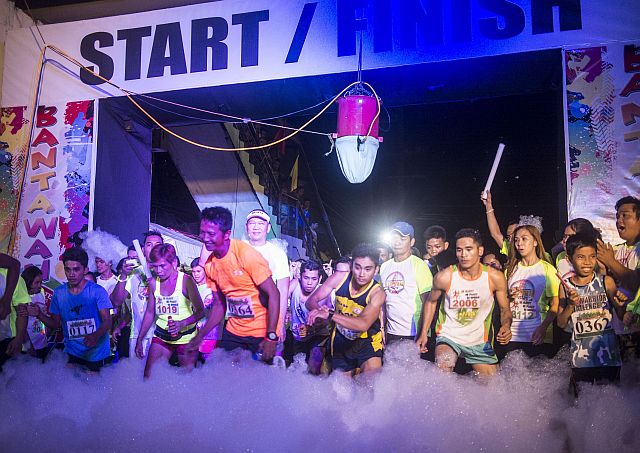 Participants run through bubble foam at the start of the first-ever Bantawan Night Fun Run in Barangay Poblacion Pardo, Cebu City last Saturday night (CDN PHOTO/CHRISTIAN MANINGO).