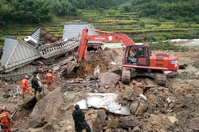 Rescuers use heavy equipment to dig in the rubble of a house that was destroyed in a landslide in Sucun village in eastern China’s Zhejiang Province, Thursday. (AP)