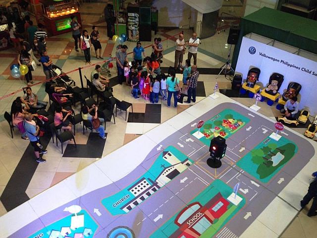 The Junior Driving Course features a miniature simulated roadway within a community, complete with road signages, stoplights, and Volkswagen push cars for the kids to use.