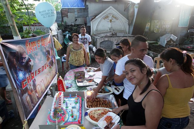 The Querubins, one of the families living right outside the Doña Pepang Cemetery, celebrate a birthday party inside the cemetery (CDN PHOTO/TONEE DESPOJO). 