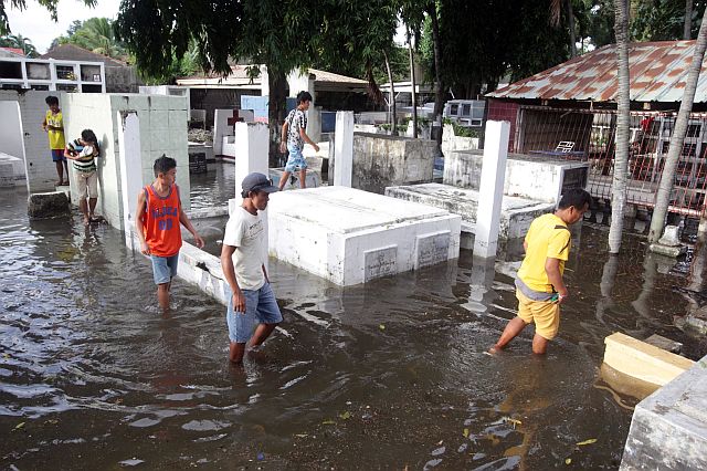 Relatives wade through the floodwaters to visit the tomb of their dearly departed in a Barangay Gun-ob cemetery in Lapu-Lapu City (CDN PHOTO/TONEE DESPOJO).