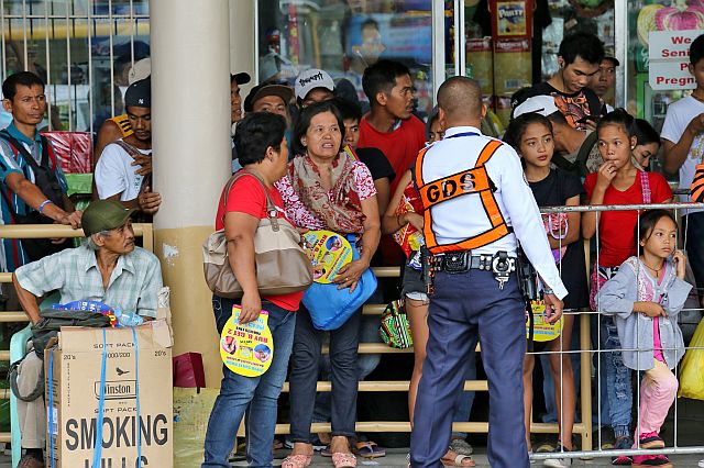 TIGHT SECURITY. A security guard holds in line a crowd of passengers at the Cebu South Bus Terminal waiting to board buses that will bring them to their hometowns for the All Saints’ Day and All Souls’ Day break (CDN PHOTO/JUNJIE MENDOZA). 