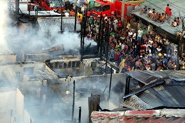 Residents of Barangay Suba could only watch helplessly as firefighters put out the last embers of the fire that burned down their homes.  (CDN PHOTO/JUNJIE MENDOZA)