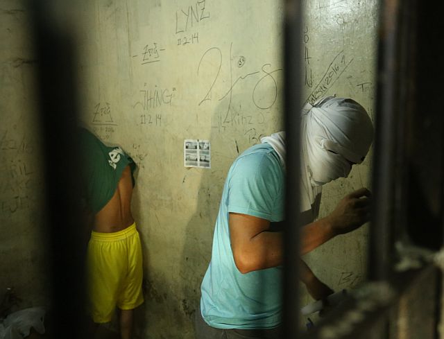 ARRESTED. PO1 Gem Querubin, who is assigned at the Mambaling Police Station in Cebu City, covers his face with a t-shirt while held inside the Cebu City Police Office’s stockade following his arrest in a drug buy-bust operation inside the house of Sharon Abella in Barangay Sambag 2, on Oct. 25, 2016. (CDN PHOTO/LITO TECSON) 