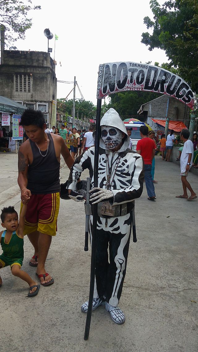 A senior who identified himself as ‘Mang Boy’ poses as the Grim Reaper bearing an anti-drug message (CDN PHOTO/NESTLE SEMILLA). 