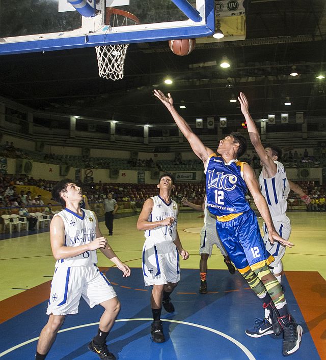 John Bryle Cuyos of University of Cebu stretches for a lay-up against three defenders from the Sacred Heart School-Ateneo de Cebu in Game 1 of the Cesafi secondary basketball tournament best-of-three championship series last night at the Cebu Coliseum (CDN PHOTO/CHRISTIAN MANINGO).