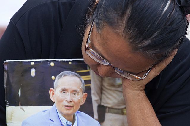 A Thai woman holds a portrait of Thai King Bhumibol Adulyadej outside Siriraj Hospital where Bhumibol had been treated in Bangkok, Thailand, Friday. (AP)