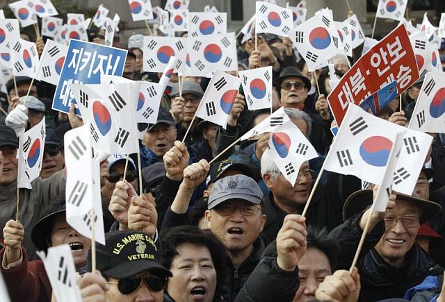 Protesters supporting South Korean President Park Geun-hye wave national flags during a rally opposing her resignation in Seoul, South Korea, Thursday (AP PHOTO).