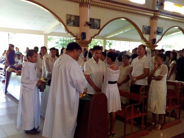 The 49 couples wait on parish priest Fr. Dennis Baricuatro to administer their wedding vows (CONTRIBUTED PHOTO). 