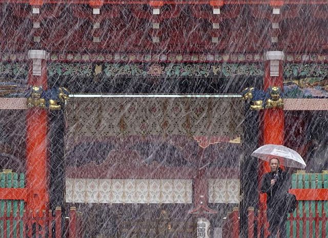 A man stands near the gate in the snow at Kanda Myojin shrine in Tokyo, Thursday. Tokyo residents have woken up to the first November snowfall in more than 50 years. (AP)
