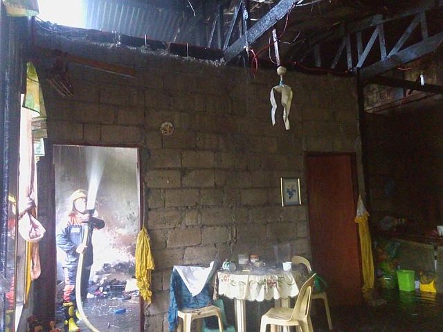 A responding fireman trains his hose at the burning house of Reynaldo Elcontro in Barangay Kalunasan, Cebu City. (CDN PHOTO/JUNJIE MENDOZA)