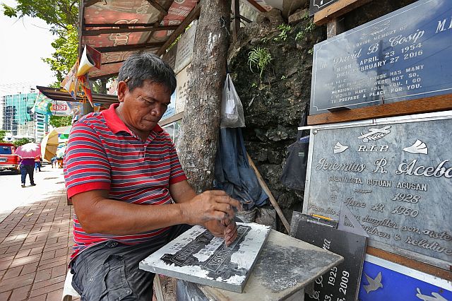 58-year-old Alberto Saga  carefully  carves a name into granite, a small business that he has had for nearly four decades.   Saga ‘s lapida making has helped send his six children through school. (CDN PHOTO/  JUNJIE MENDOZA)