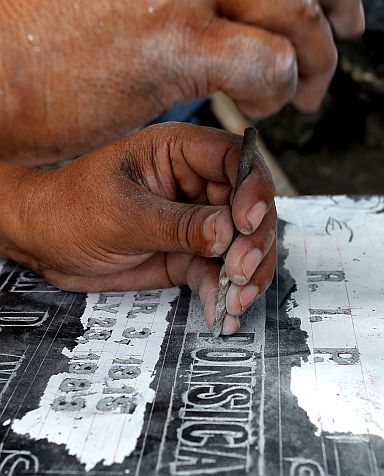 58-year-old Alberto Saga  carefully  carves a name into granite, a small business that he has had for nearly four decades.   Saga ‘s lapida making has helped send his six children through school. (CDN PHOTO / JUNJIE MENDOZA)