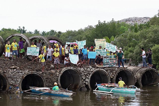 NO ENTRY. Fishermen of Barangays Cogon Pardo, Mambaling and Pasil with their families protest the culvert bridge at the South Road Properties (SRP) service road leading to the Inayawan Landfill because it prevents their bancas from passing through the Talisay City side so they can fish (CDN PHOTO/JUNJIE MENDOZA). 