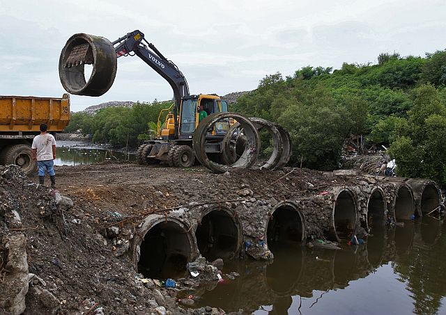 A backhoe operator unloads a culvert from a dump truck as the construction of the culvert bridge that connects the South Road Properties to the Inayawan Landfill continues. (CDN PHOTO/JUNJIE MENDOZA)