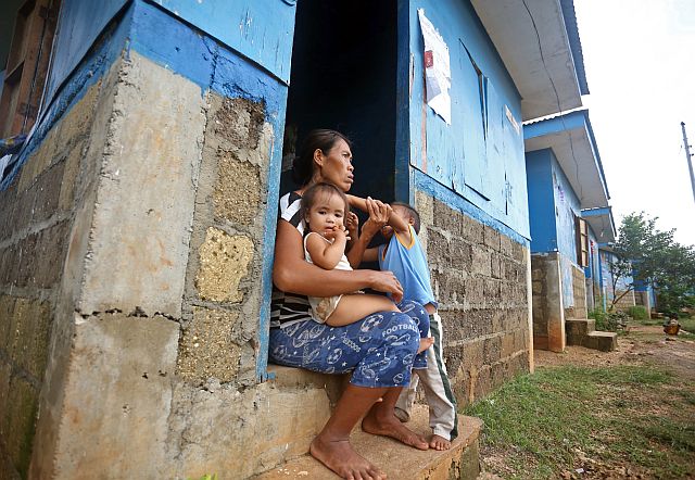 Dolores DerDer, a mother of two,  who is  among the  beneficiaries of housing units from private sector donors who had quickly responded to the call for help after the typhoon, sits outside her new home (CDN PHOTO/LITO TECSON). 