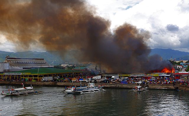 A thick black smoke that came from the burning houses at Barangay Suba at the back of Pasil fish market blows out on the sky . (CDN PHOTO/JUNJIE MENDOZA)