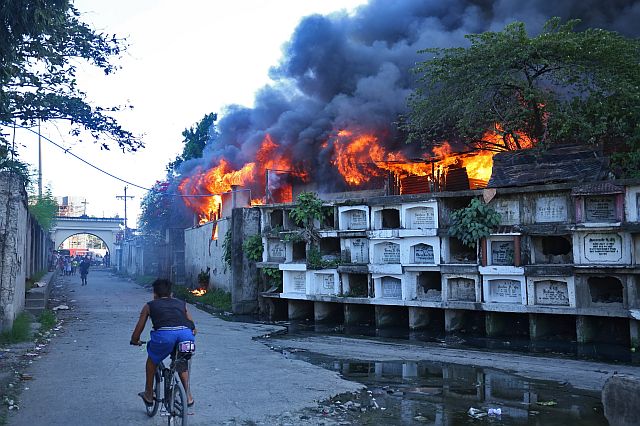 A bike rider speeds his way out of the Ludo Cemetery where a fire razes several houses near the area in Barangay Carreta.  (CDN PHOTO/LITO TECSON)
