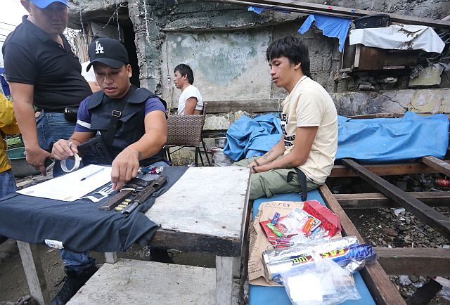 Francis John  Villanueva, 21, was arrested with his father, Rewel alias Peheng  (background) after they were caught in possession of several grams of shabu and a .45 caliber pistol during a raid in Sitio Sta. Teresita, Barangay Tejero.  The two were linked by police to the illegal drug trade of Rewel’s wife, Jocelyn, and her brother Gener Rondina.   Jocelyn and Gener are both  children of retired SPO4 Generoso Rondina who cries foul over the death of Gener. (CDN PHOTO/LITO TECSON). 