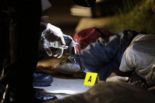 A policeman checks the gun recovered from one of two unidentified drug suspects after they were shot dead by police as they tried to evade a checkpoint in Quezon City in this Sept. 6, 2016 photo. (INQUIRER.NET) 