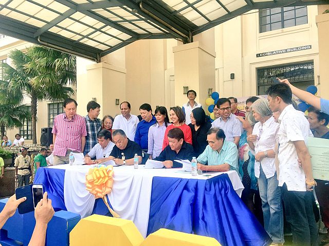 Cebu City and Cebu Province officials sign the MOA for the 93-1 land swap deal in front of urban poor groups on Wednesday. (CDN PHOTO/JOSE SANTINO S. BUNACHITA)