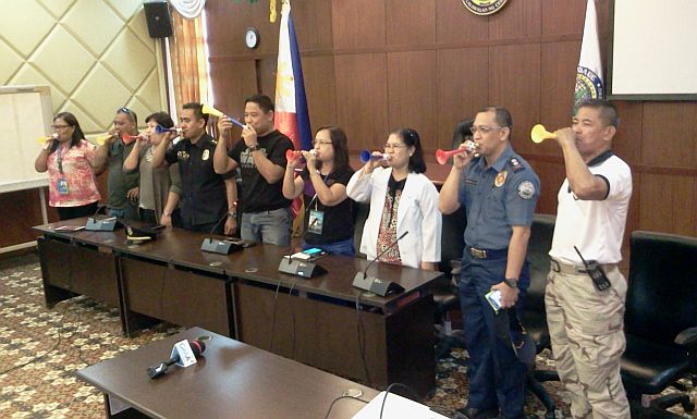 Mandaue acting Mayor Carlo Fortuna (5th from left) leads officials in blowing the horn as he and the other officals call for the  public to use them instead of firecrackers. (CDN PHOTO/NORMAN MENDOZA) 