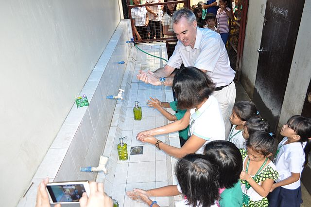 Patrick Egan, Viten Evides International project director, and Joy Ventic of MCWD teach the grade 1 pupils of Inayawan Elementary School the proper way of washing their hands during a handwashing activity in the school. 
