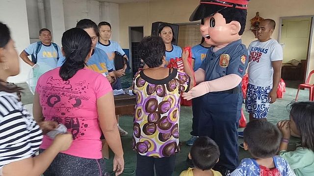 Mandaue City Police Office’s mascot, SPO1 Mandaue, helps distribute the bundles of joy to the beneficiaries. ( CDN PHOTO/NORMAN MENDOZA). 