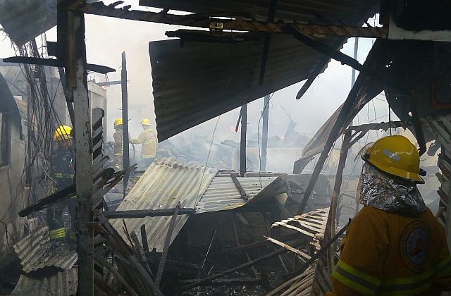 Firefighters checks on structures in Barangay Apas which was hit by fire past 2 p.m. on Monday. At least 60 houses were damaged. (CDN PHOTO/TONEE DESPOJO)