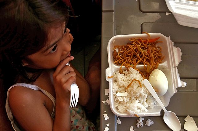 BREAKFAST. A girl eats her food pack containing cooked rice, noodles, and an egg for breakfast. (CDN PHOTO/JUNJIE MENDOZA).