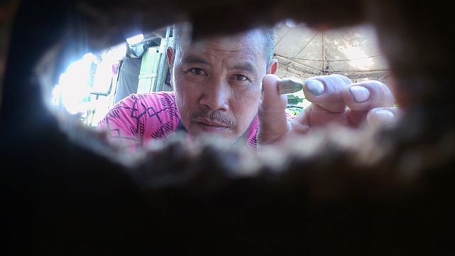 Narciso Batucan shows the slug of a .45 caliber bullet behind a bullet hole on the wall of his house where the bullet passed. His seven-year-old son was killed by a stray bullet which came from motorcycle-riding men who were chasing a teenager who was an alleged drug pusher. (CDN PHOTO/TONEE DESPOJO)