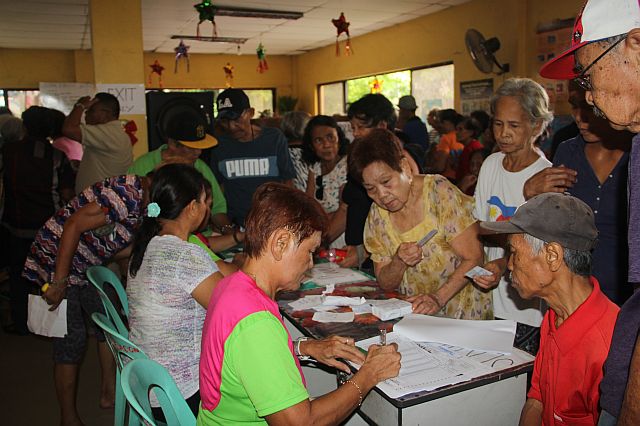 Social welfare personnel distribute the cash aid to Lapu-Lapu City’s seniors.  (CDN PHOTO/NORMAN V. MENDOZA)