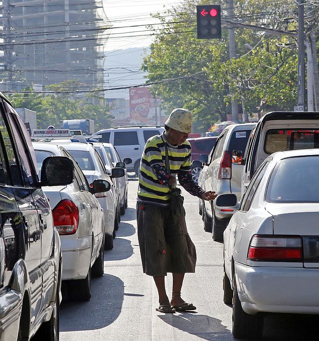 A beggar asks for alms from motorists and commuters along Osmeña Boulevard in Cebu City. (CDN FILE PHOTO)