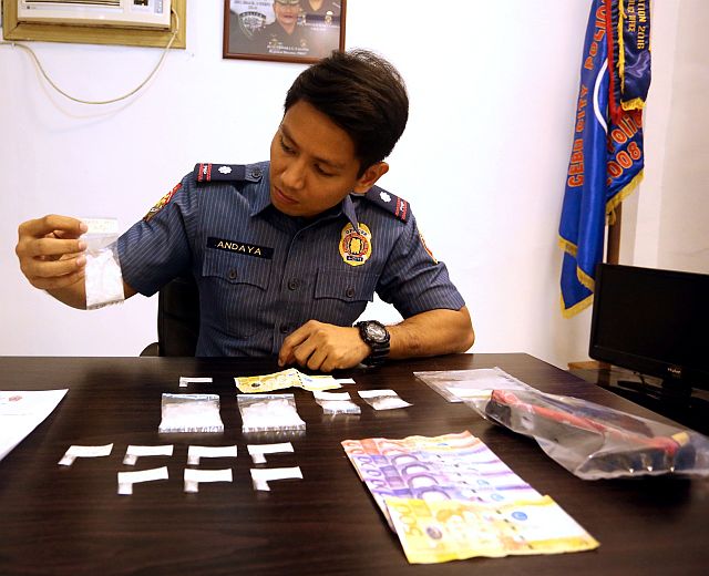 San Nicolas police station Chief Insp. Keith Andaya presents the confiscated items from suspected drug pusher Andrew Bonny Rebucas Abejo in Barangay Pasil. (CDN PHOTO/LITO TECSON)