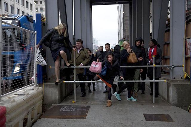 People take a shortcut through building works beside a narrow section of pavement at the north end of London Bridge in London, Monday. Millions of commuters are facing delays and frustration as a strike by London Underground station staff shuts down much of the city’s subway network. (AP PHOTO). 