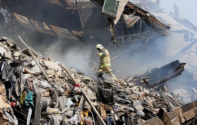 A firefighter walks through the debris of Iran’s oldest high-rise, the 15-story Plasco building in central Tehran, after it collapsed on January 19, 2017 following a fire. (AFP) 