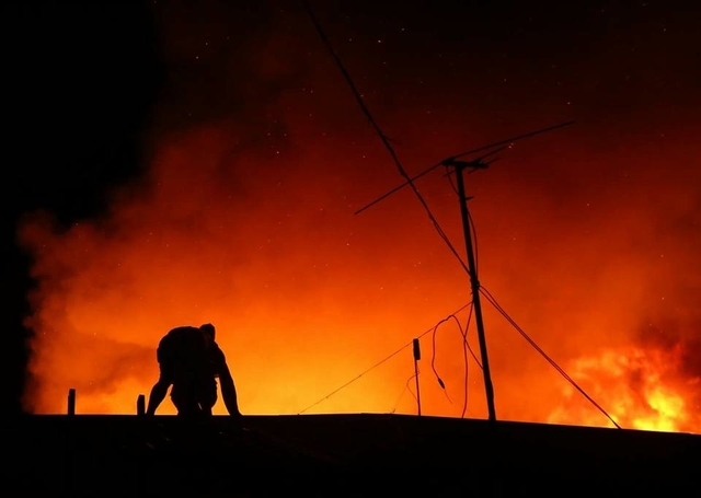 Silhouette of man on top of a house about to stand up to look at the fire (CDN PHOTO/TONEE DESPOJO).