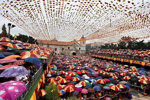 Devotees take their umbrellas out as light rain brought about by LPA Auring washes over the Pilgrim Center (CDN PHOTO/JUNJIE MENDOZA). 