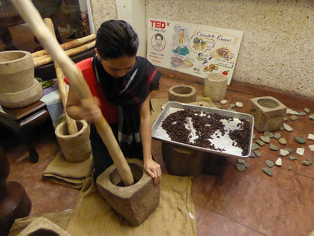 Raquel pounding cocoa nibs using lusong and alho.  (JASON OLIVER DELA CRUZ)