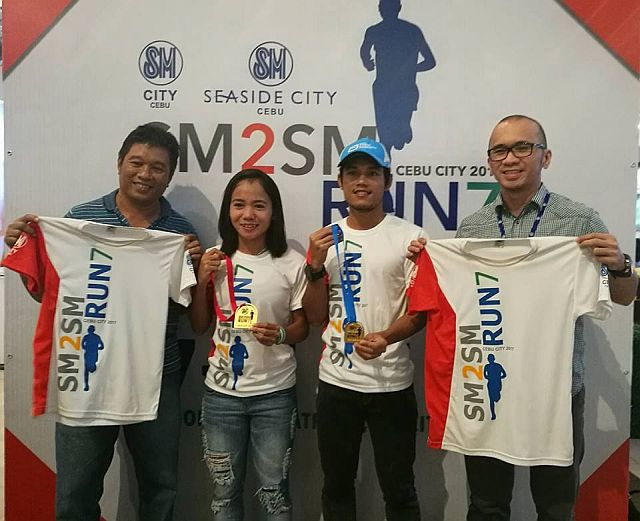 Race director Joel Baring (left to right), Mary Joy Tabal, John Philip Dueñas and SM City Cebu assistant mall manager Michael Manlangit show the singlets and finishers medal for next month’s SM2SM Run at the SM City Cebu. (CDN PHOTO/GLENDALE G. ROSAL)