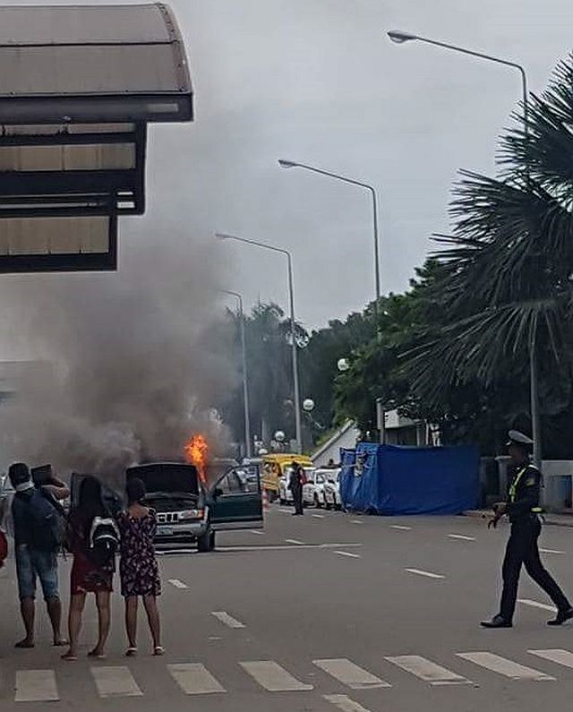 Travelers watch as a green Kia Sportage caught fire along the Domestic Departure drop off area of the Mactan Cebu International Airport on Saturday afternoon. (CONTRIBUTED PHOTO)