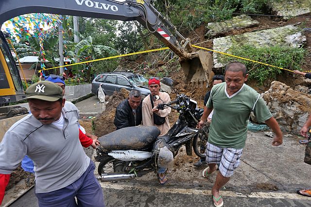 Residents and barangay employees pull out one of two motorcycles that were buried by the landslide. (CDN PHOTO/JUNJIE MENDOZA)