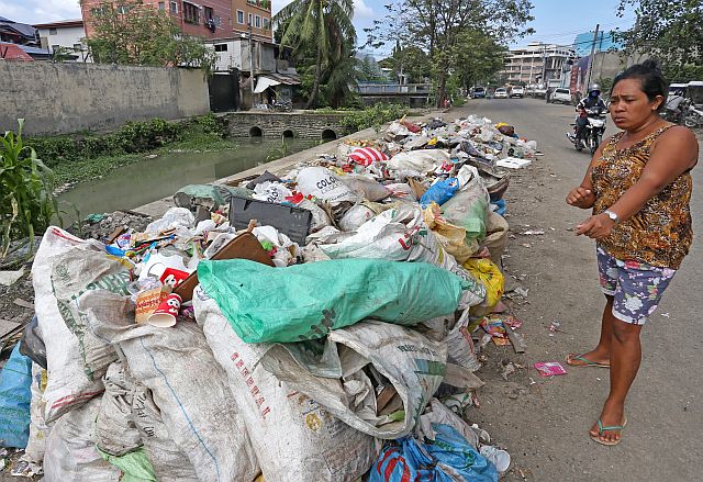  A  resident of Sitio Villagonzalo 2, Barangay Tejero,  complains  against the  mounds of garbage that are left by  the road along  David C. Gaisano Street.  Residents and motorists claim that the trash has been lying there  before the Sinulog celebration and only half has been collected by City Hall’s Department of Public Services (DPS). (CDN PHOTO/JUNJIE MENDOZA)