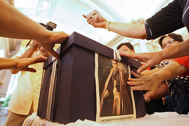 Devotees gather around an image of Archbishop Teofilo Camomot posted on a box containing documents that would be sent to Rome lobbying for the cause of his sainthood in this Feb. 2014 file photo.