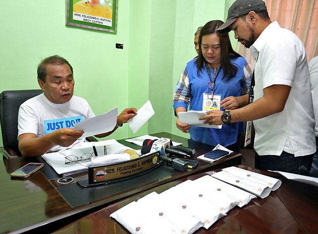  Ermita barangay Capt. Felicisimo Rupinta (seated) receives his suspension order  from Emma Joyevelyn Calvo and Jamaes Andrew Andaya of DILG Cebu City office. The suspension orders for his seven councilors are on his table. (CDN PHOTO/JUNJIE MENDOZA)