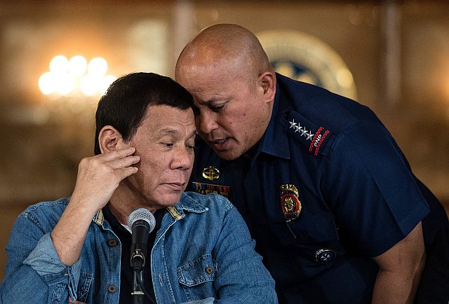 Philippine President Rodrigo Duterte (L) talks to Philippine National Police (PNP) Director General Ronald Dela Rosa (R) during a press conference at the Malacanang palace in Manila on January 30, 2017.  Philippine's President Rodrigo Duterte on January 30, 2017 extended his deadly drug war until the last day of his term in 2022, but conceded the police force acting as his frontline troops was "corrupt to the core". Thousands of people have died in the crackdown that began when Duterte took office in the middle of last year, with rights groups warning police are carrying out extrajudicial killings not just to fight crime but to aid their own corrupt activities. / AFP PHOTO / POOL / NOEL CELIS