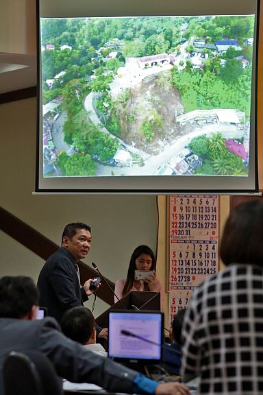City Councilor Jerry Guardo shows photos of the landslide in Sitio Garaje, Barangay Busay during a privilege speech in the City Council. (CDN PHOTO/JUNJIE MENDOZA)
