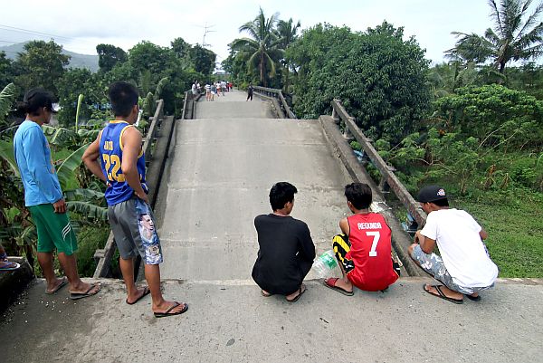 Residents stand on one end of a bridge, linking the city of Surigao to nearby towns, which was damaged after a 6.7-magnitude earthquake struck overnight in Surigao City in southern island of Mindanao on February 11, 2017. (AP)